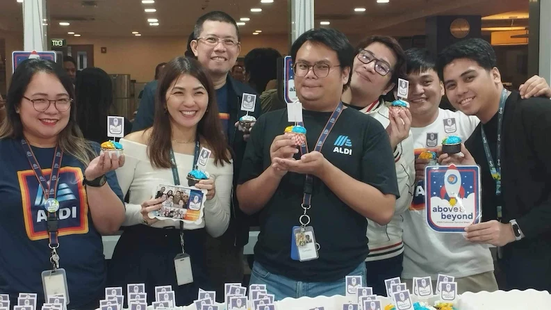 TTEC employees holding a cup cake during a company celebration.