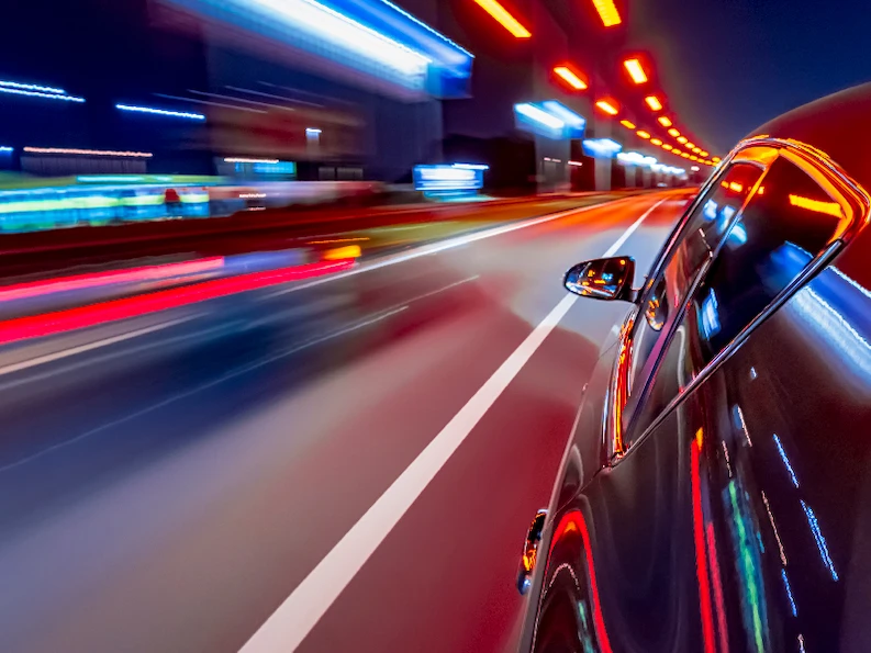 A car driving past lights on the highway