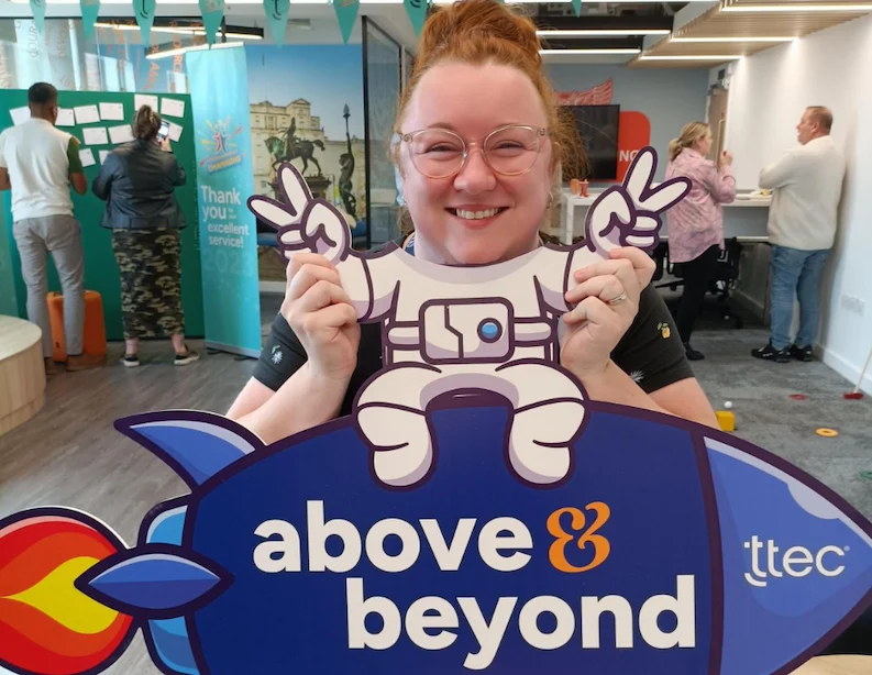 TTEC team member holding a sign saying"above and beyond"