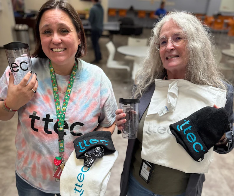 TTEC team members holding company swags.