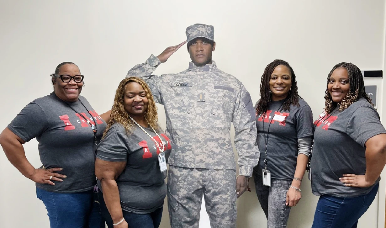 Group of employees standing next to poster of military officer