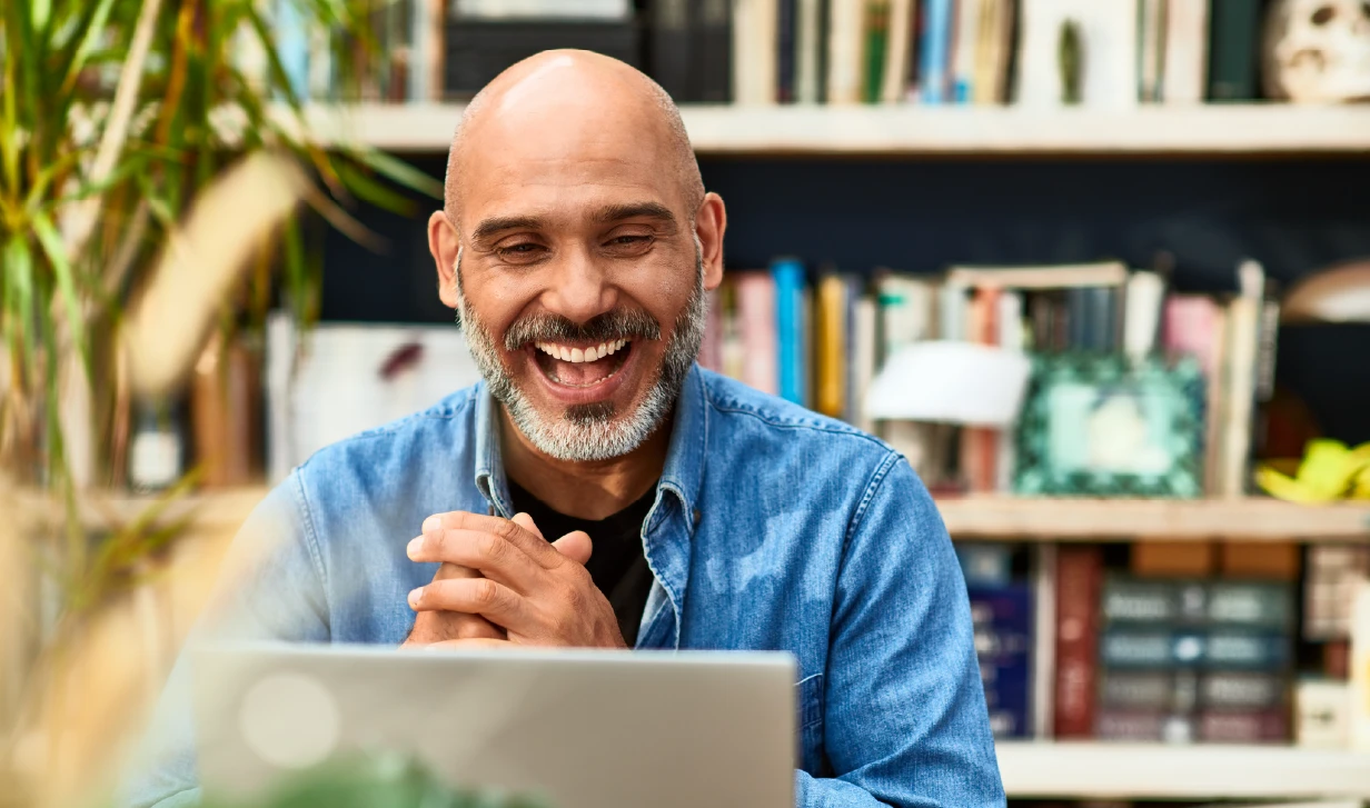 Man in home office sitting at table using a laptop