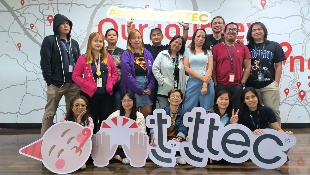 Group of TTEC employees posing together holding large TTEC letter props.