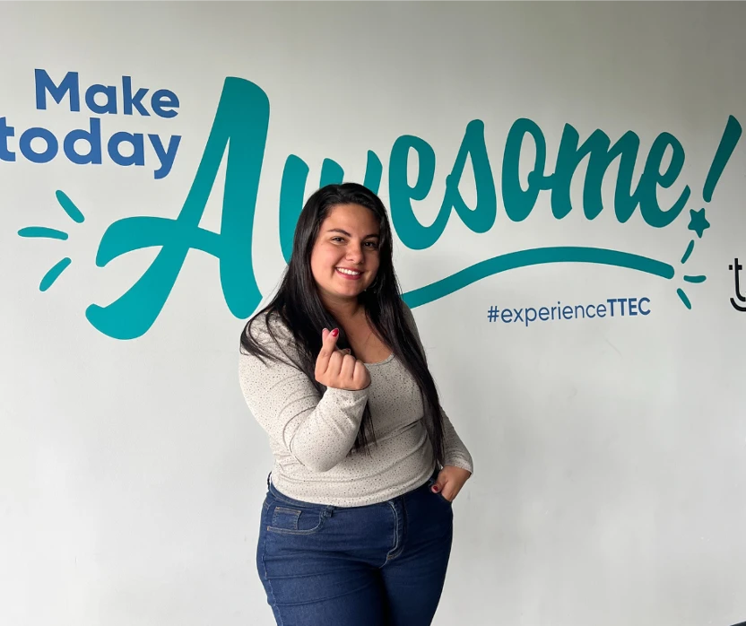 TTEC team member smiling in front of "Make today Awesome!" wall.