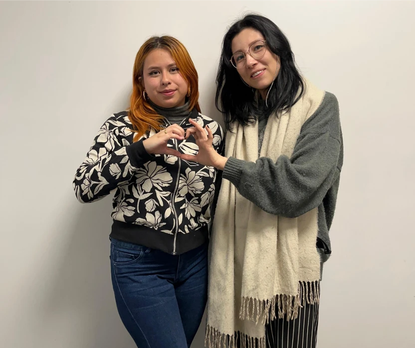 Two TTEC employees making a heart shape with their hands together.