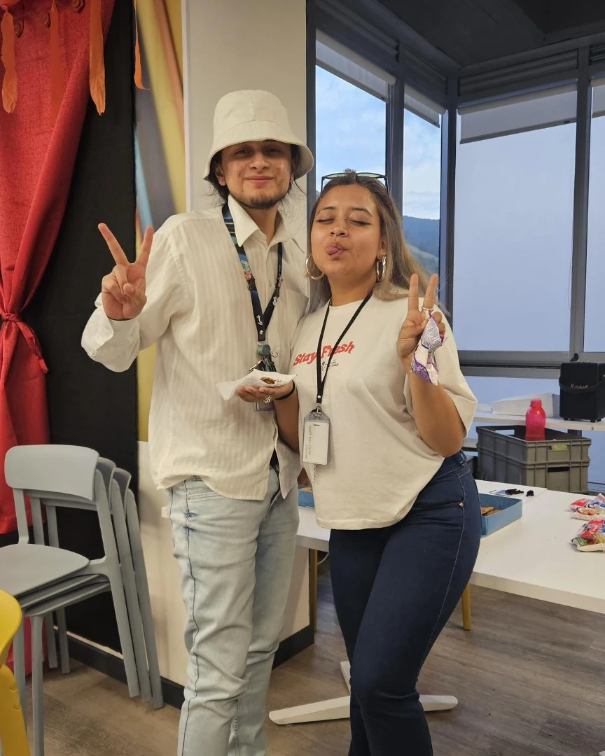 Two happy TTEC employees making peace signs in an office.