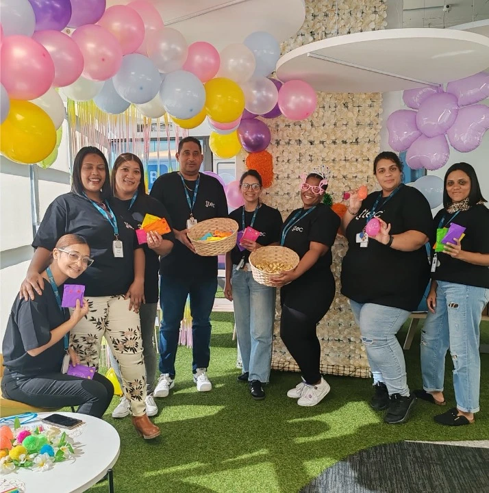 A happy group of people in TTEC shirts posing with balloons and gift baskets.
