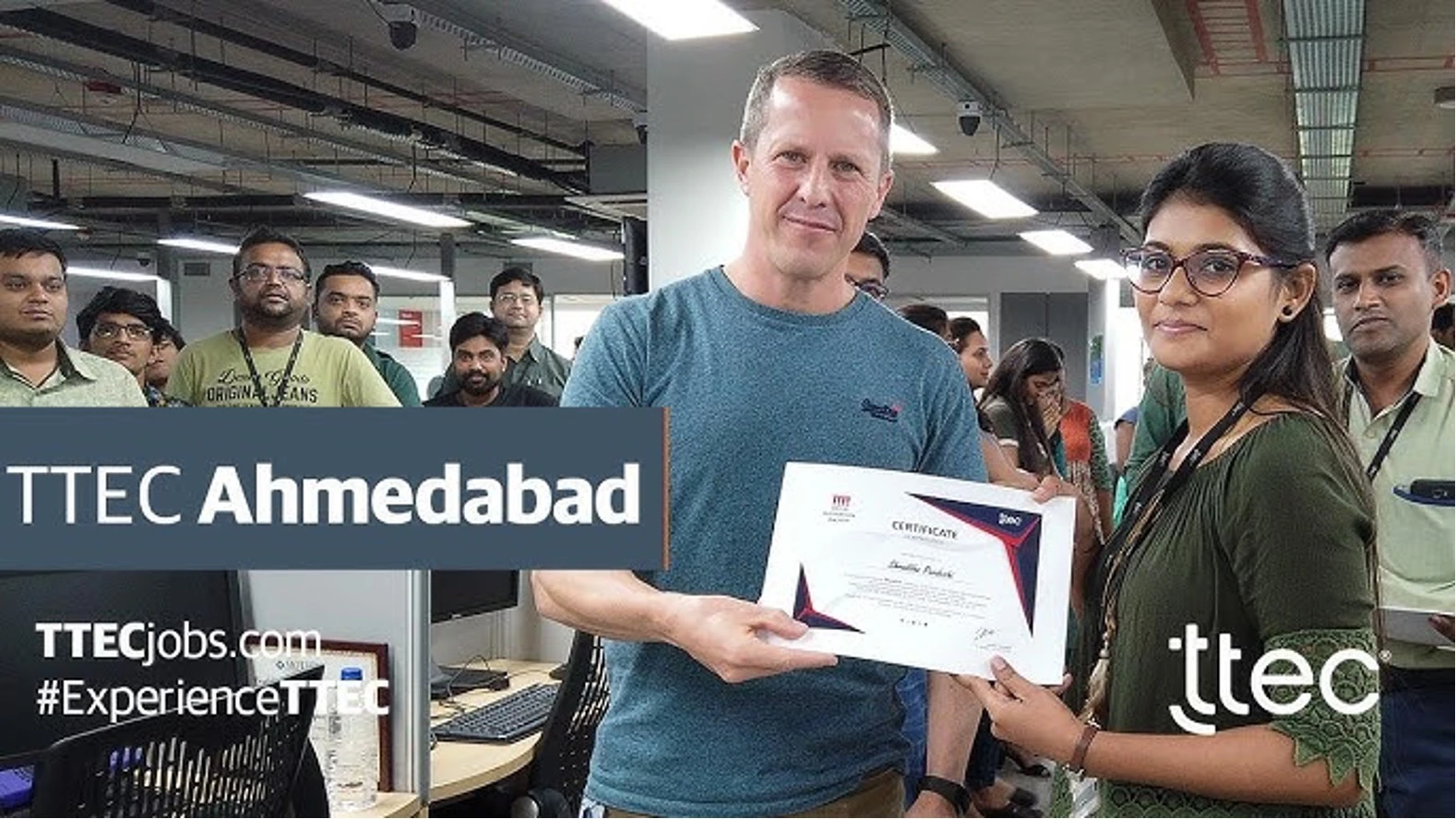 Employee at TTEC Ahmedabad receiving a certificate in an office setting.