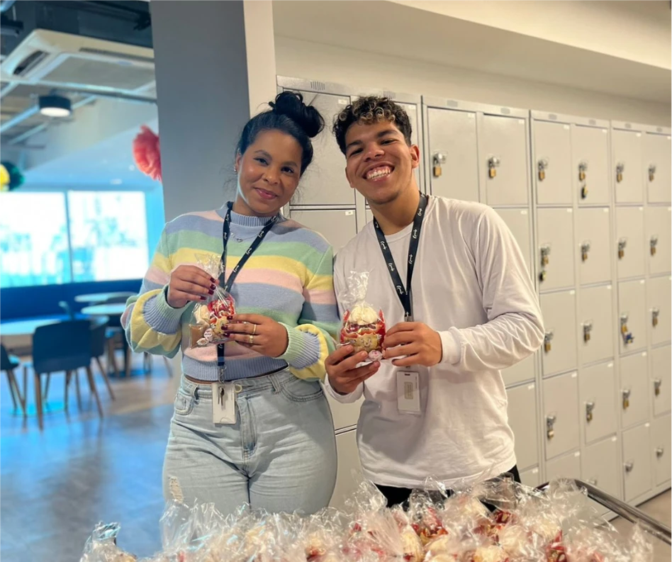 Two TTEC employees holding cupcakes in hand and smiling.
