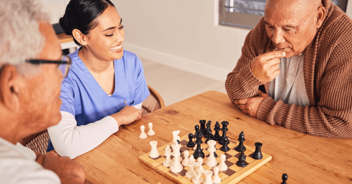 Ciena employee watching two residents play chess