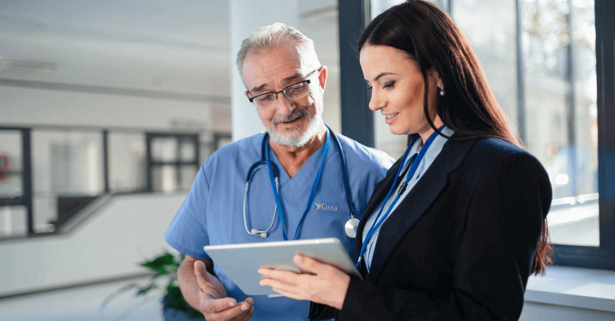 Nurse and business professional looking at tablet together.