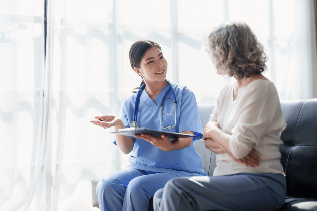 Nurse passing forms to a woman seated on a couch