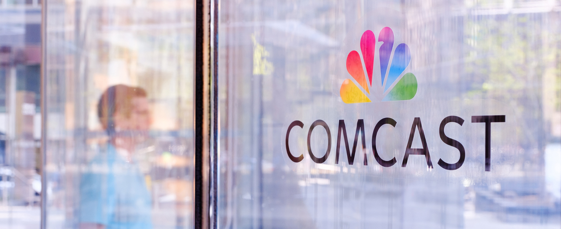 reflection of man in window with Comcast logo
