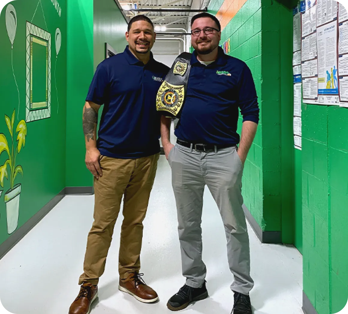 Employees smiling for the camera holding a trophy belt