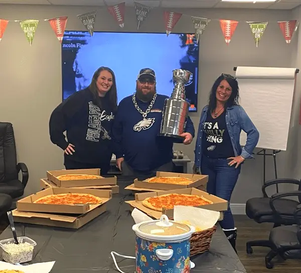 Employees smiling for the camera carrying a trophy