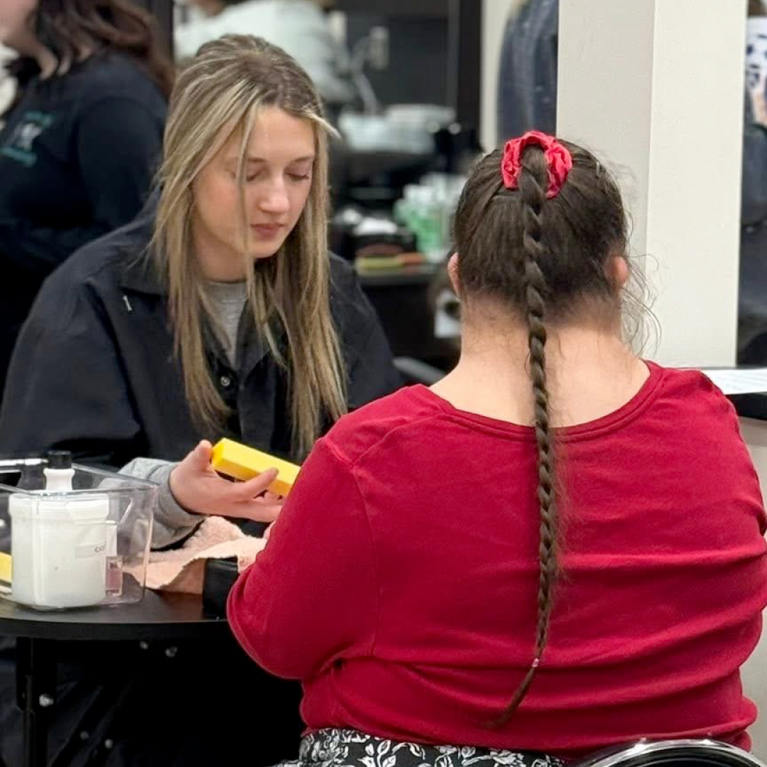 VIP attendee sits facing away from the camera with student giving her a service