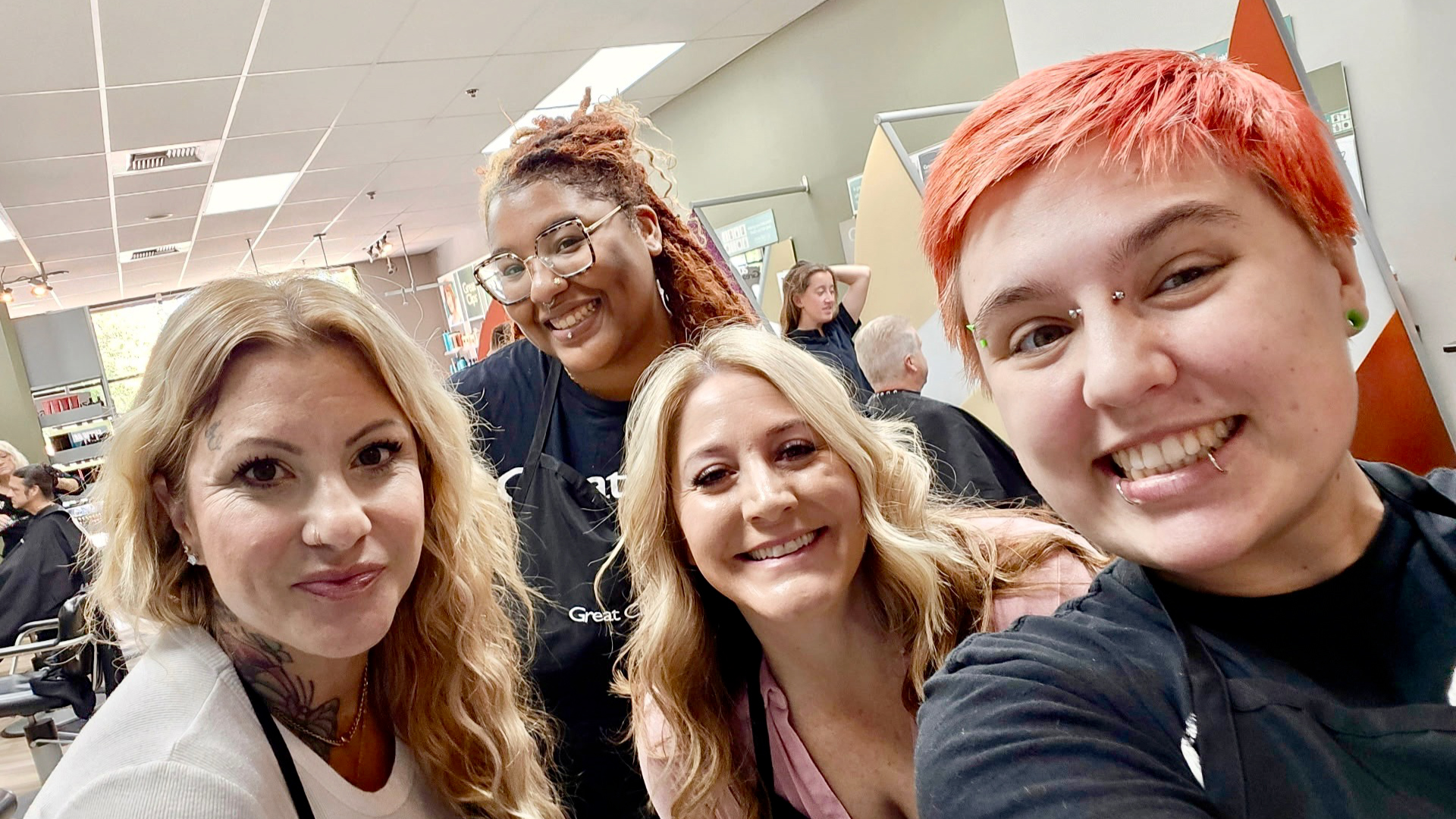 Trinity smiles and takes a selfie with team members in her salon