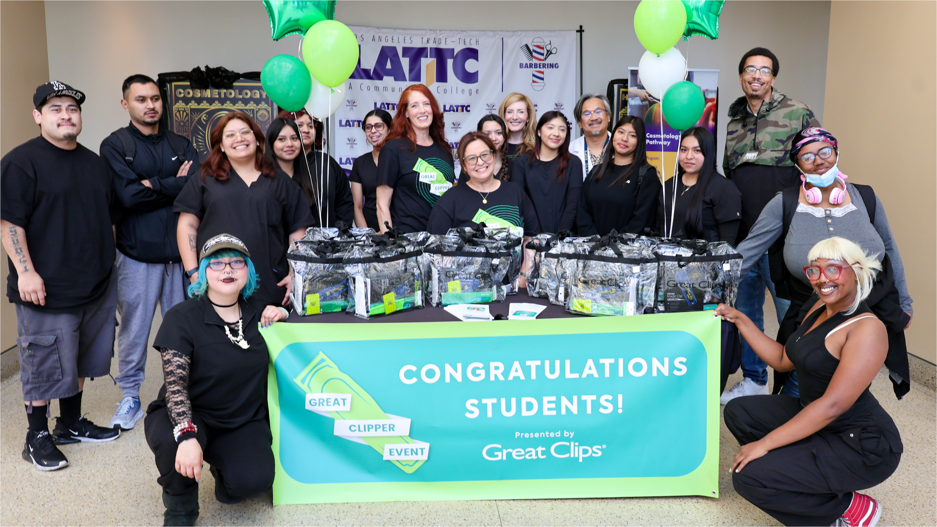 Smiling students holding gift of clippers stand in large group with celebration banner that says "Congratulations, Students"