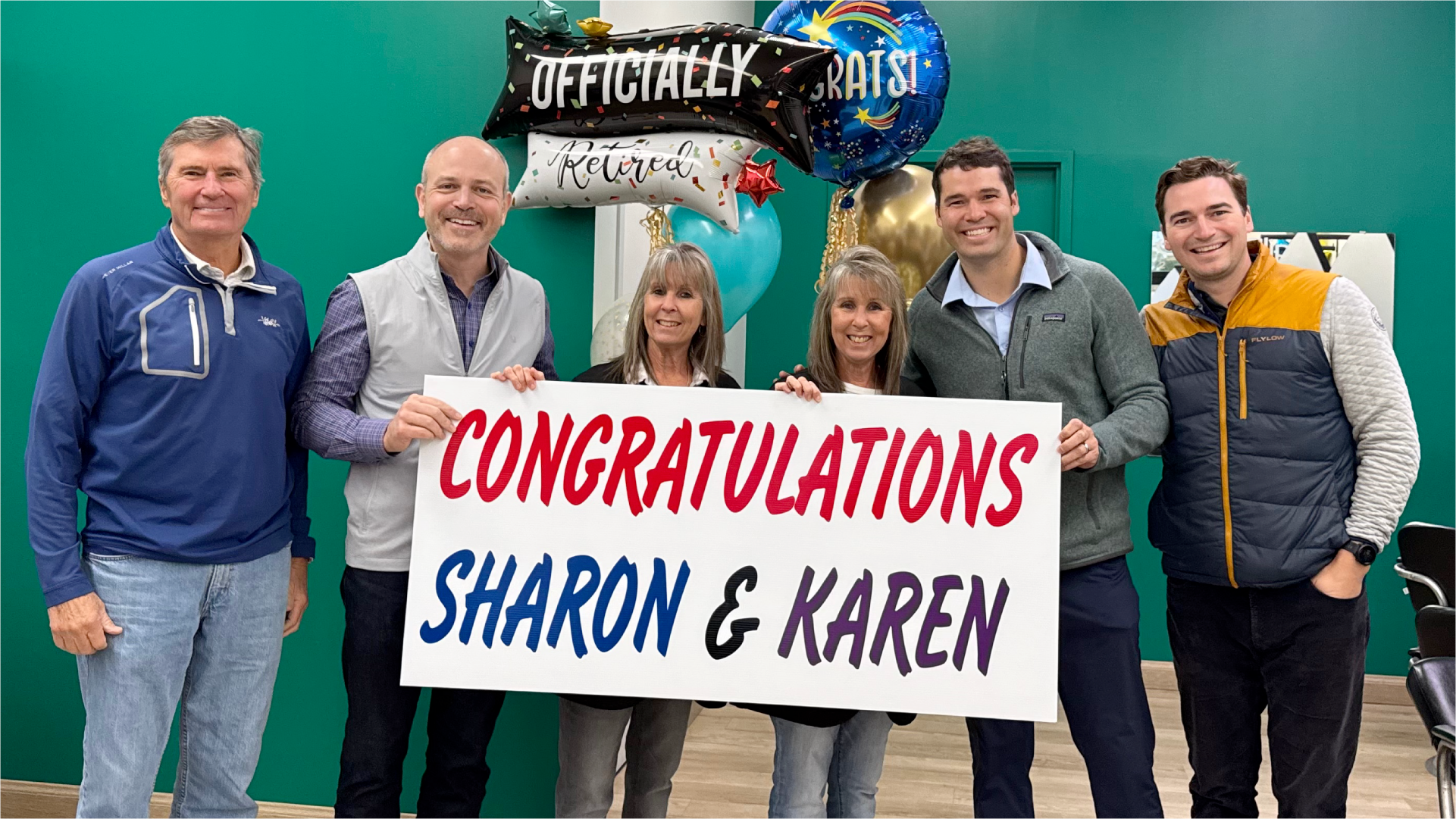 Smiling twin stylists with franchisees and Great Clips leaders, inside a Great Clips salon