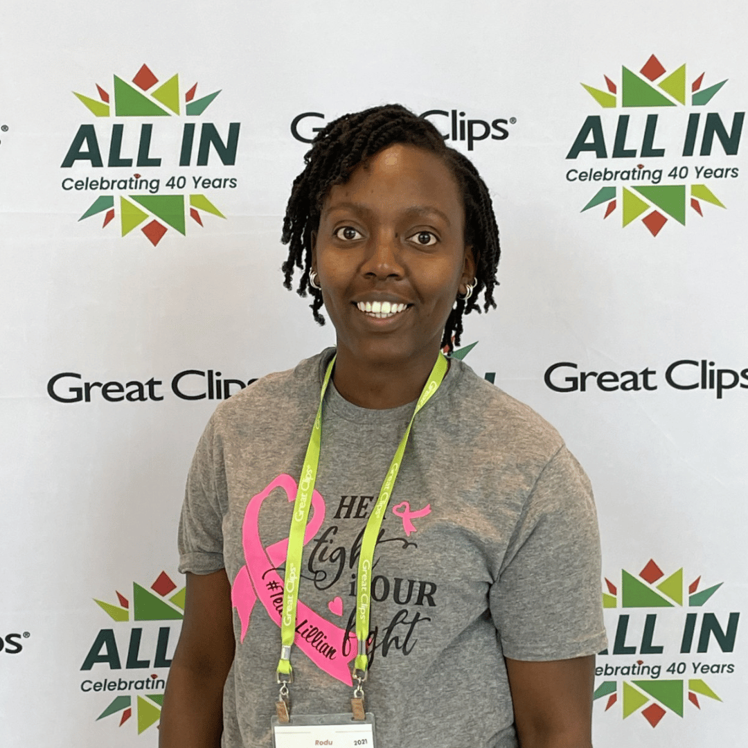 Rodu, a stylist, smiling in front of Great Clips backdrop
