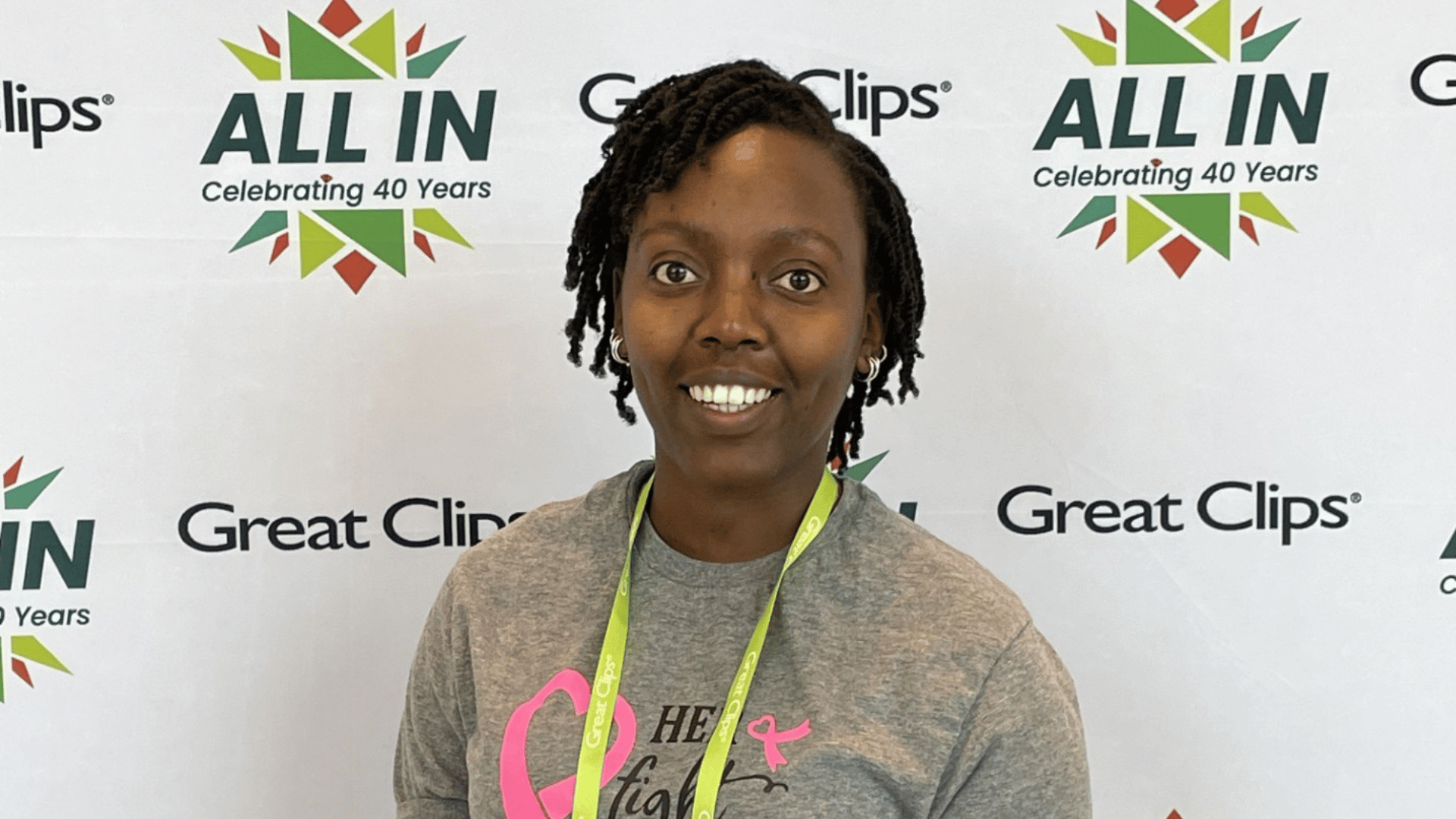Stylist Rodu smiles in front of Great Clips backdrop