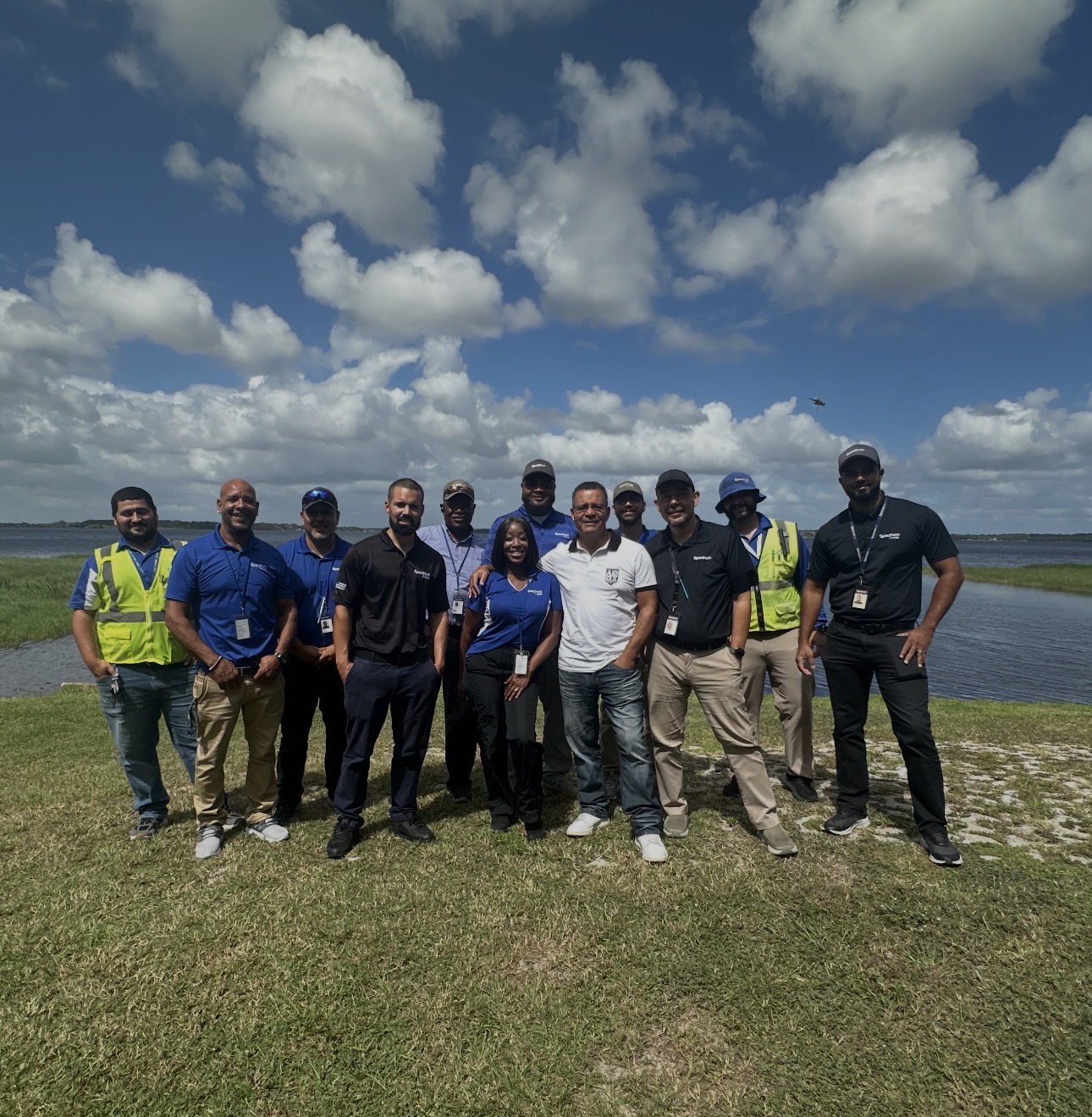 Lysander and his team pose on a sunny day in front of a body of water