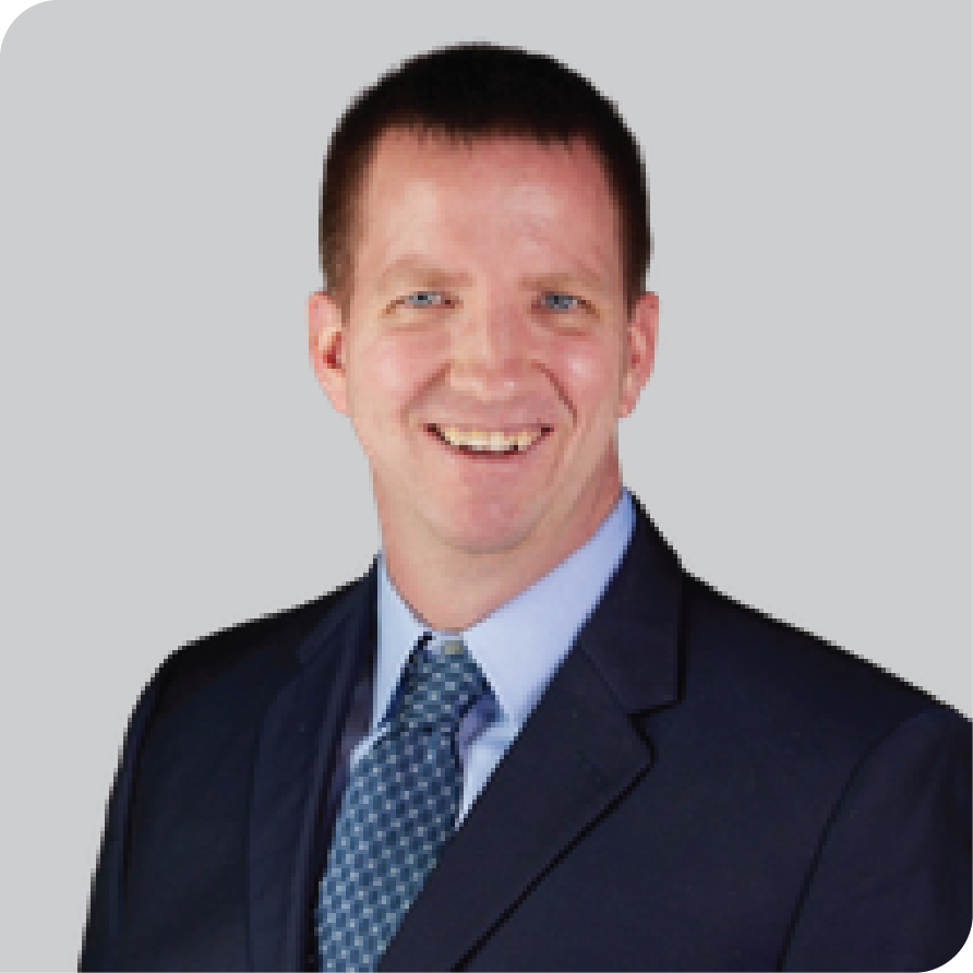White man in blue suit, tie and shirt smile at camera