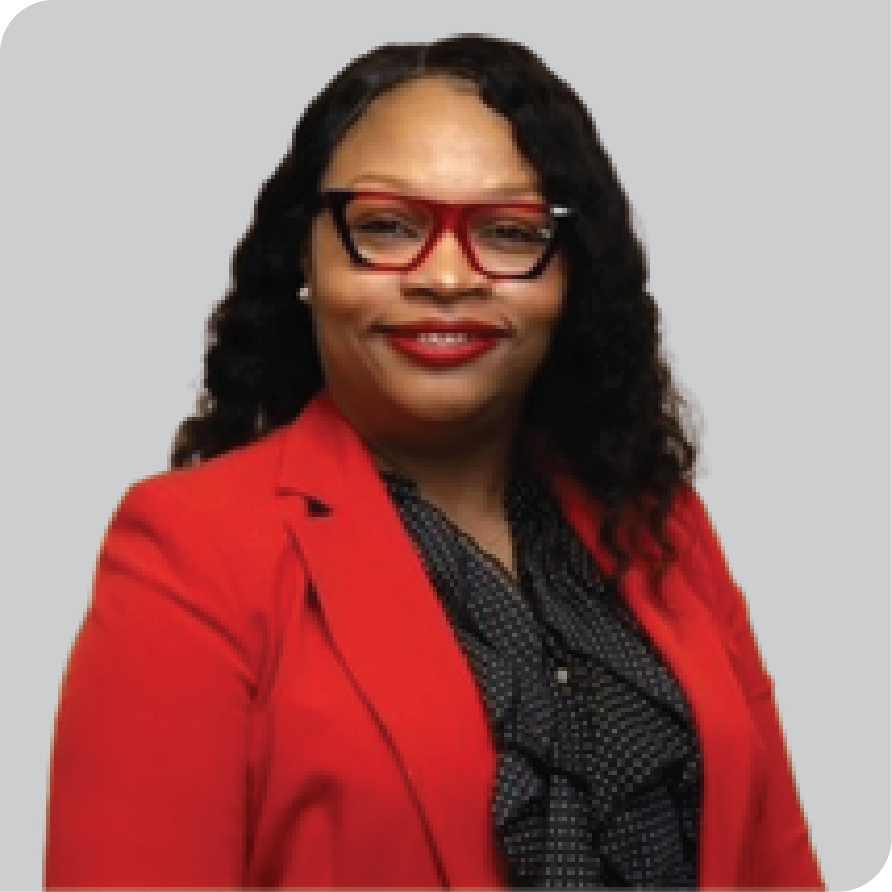 Black woman with red and black glasses in red jacket and black and white polka dot shirt smiles at camera