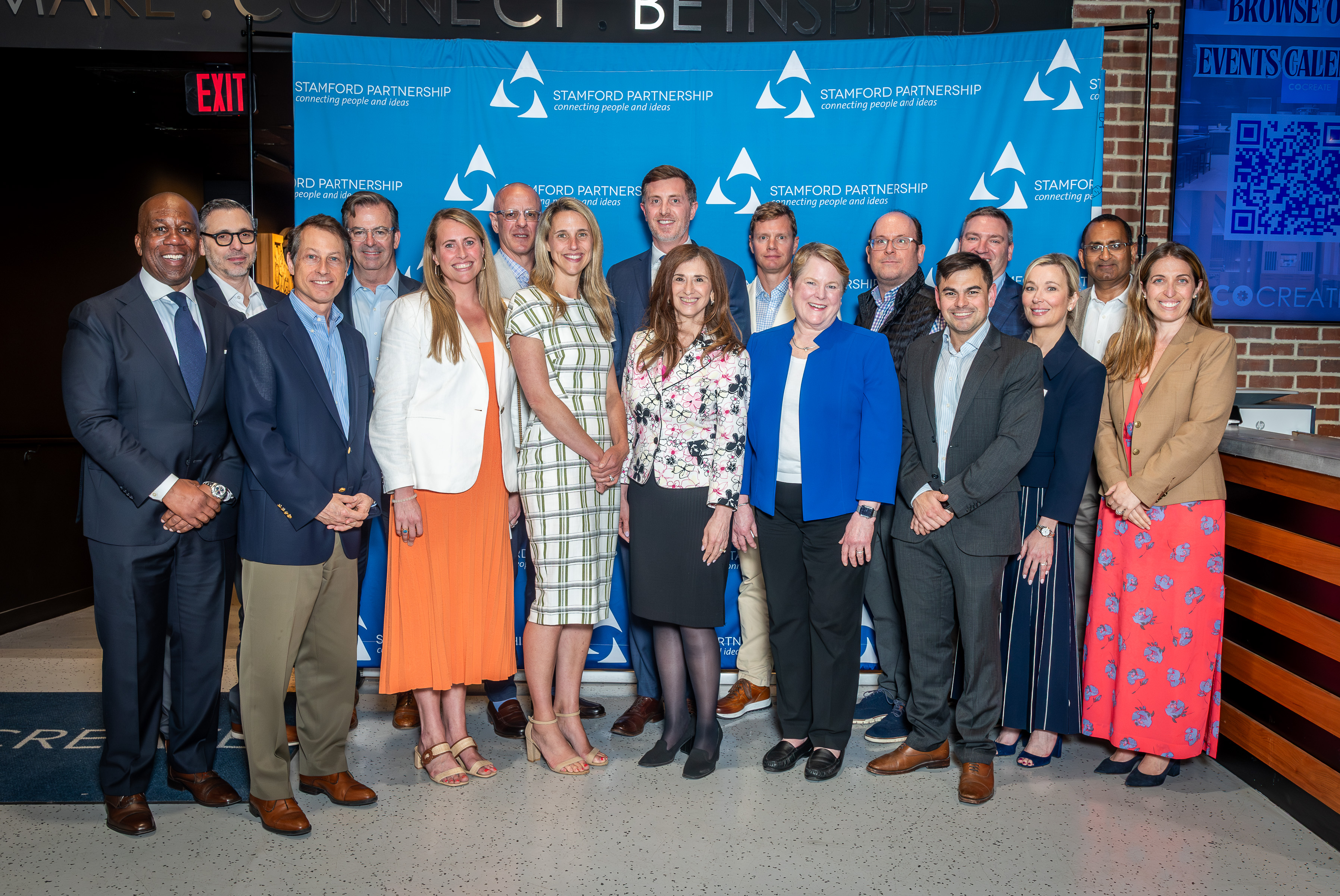 A group of attendees pose in front of step and repeat at 2026 Stamford Partnership event