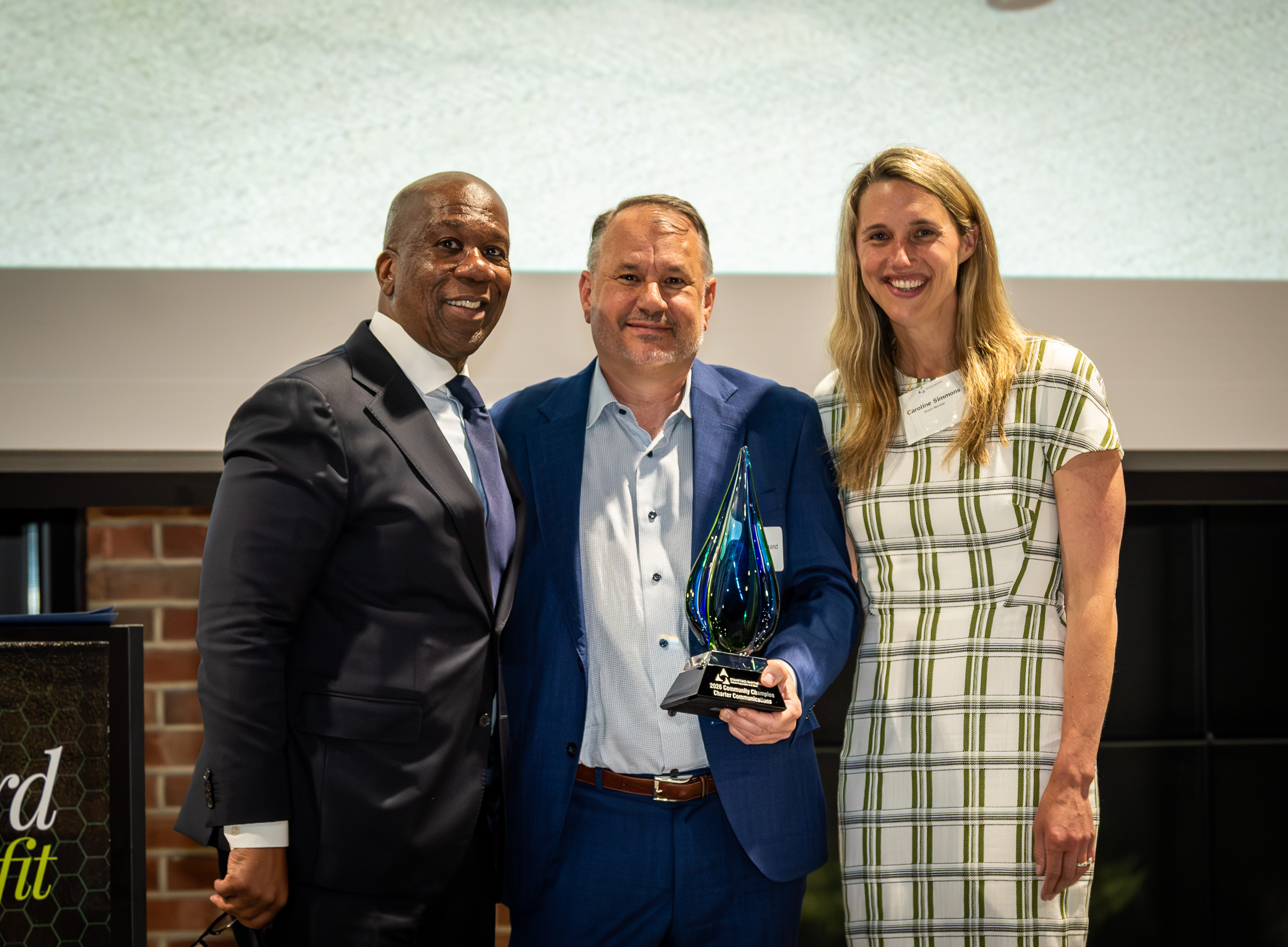 African American man, white man holding award, white woman pose for photographer