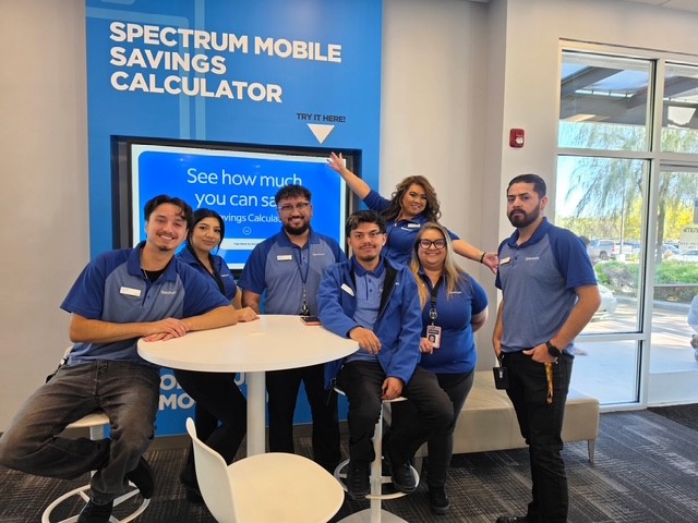 Priscilla and her team at the La Quinta, CA, Spectrum Store pose in front of a Mobile poster