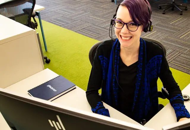 spectrum call center employee with a headset on smiling at the camera at her desk