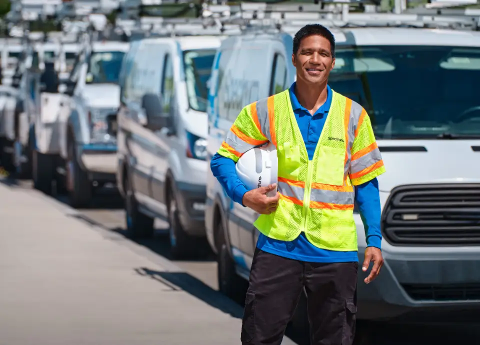 field technician smiling in front of Spectrum vans