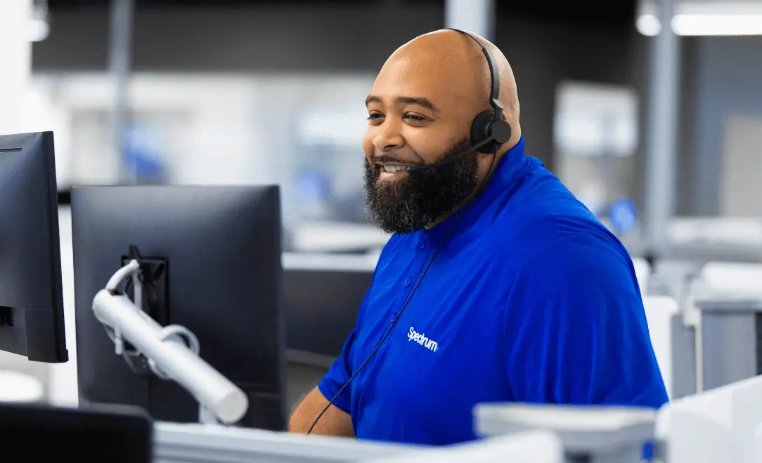 spectrum employee smiling with a headset on while looking at a computer