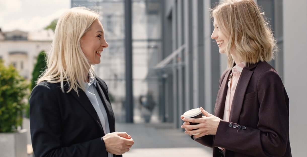 Two women in business attire chatting