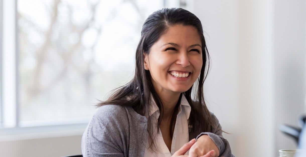 Woman employee smiling and presenting to other colleagues