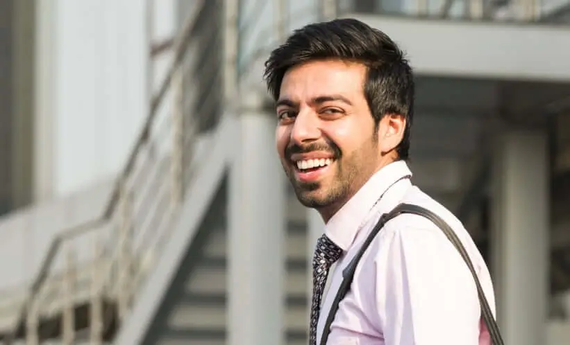young man with tie and collared shirt looking back at camera smiling