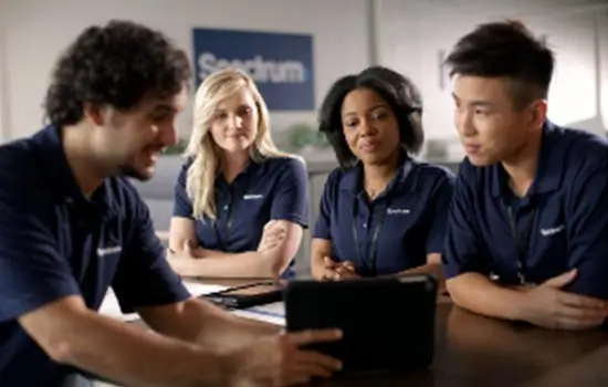 four spectrum sales employees reviewing a tablet together in a spectrum office