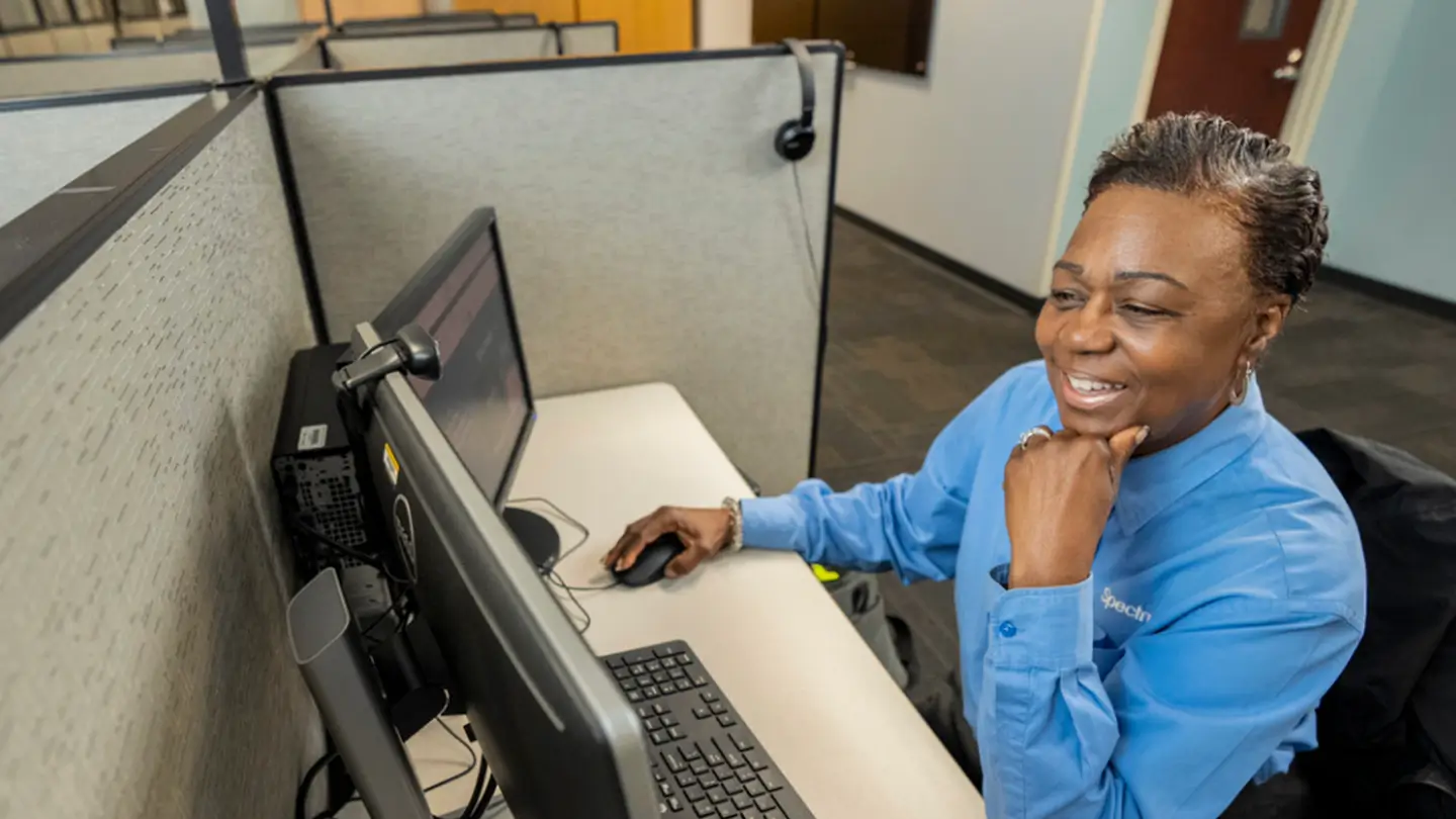 female employee smiling while sitting at desk viewing 2 screens