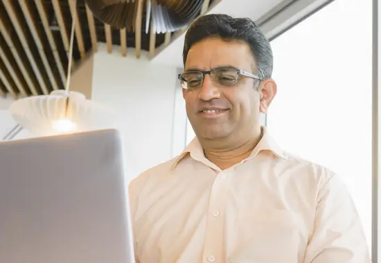 Man looking at a laptop in a pink shirt