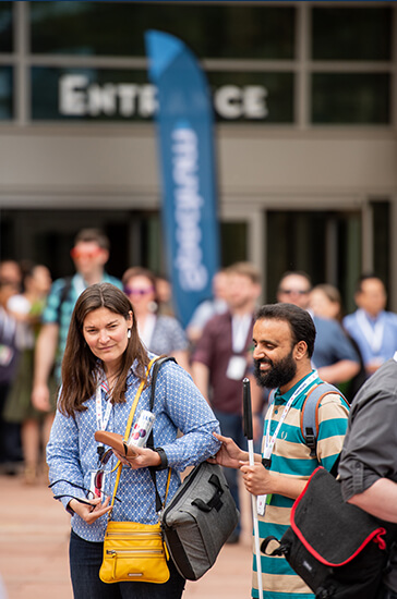 Image of a sighted Spectrum employee guiding a visually impaired Spectrum employee from one building to another