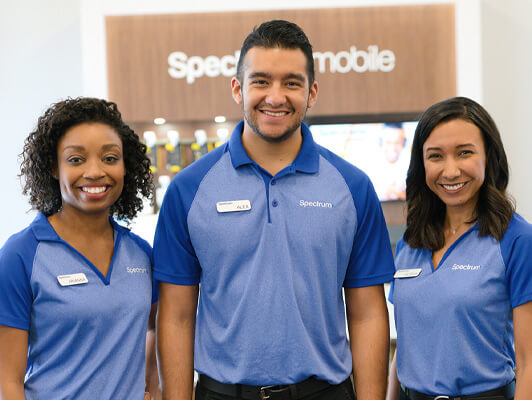 Three employees standing together in Spectrum attire and smiling