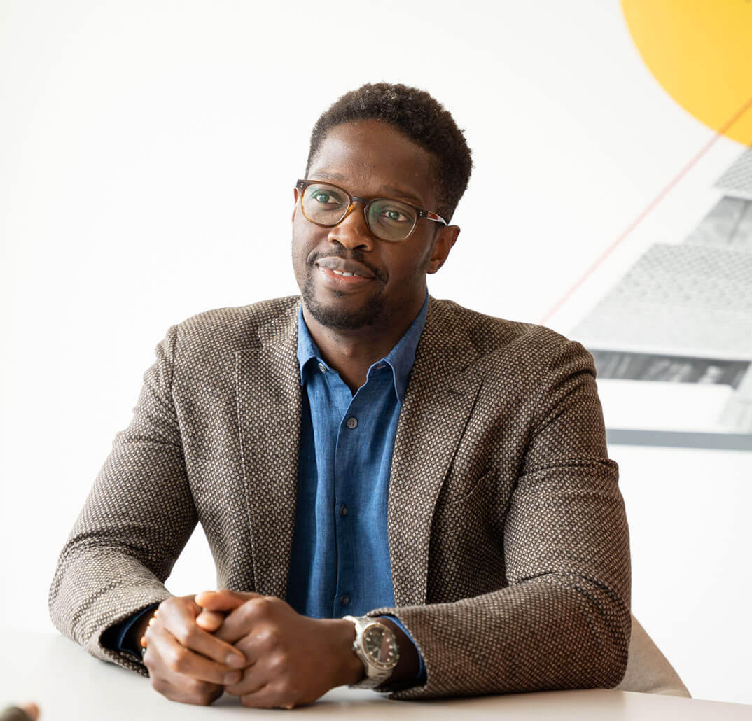 Male employee sitting down with hands together on the table