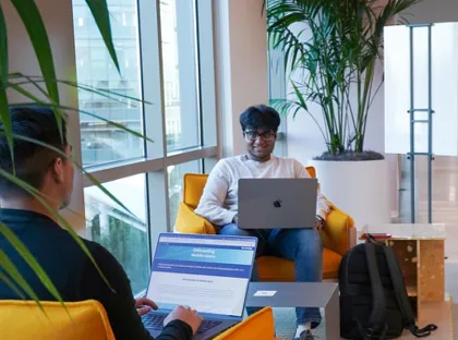 Two people working in the lounge together on their laptops