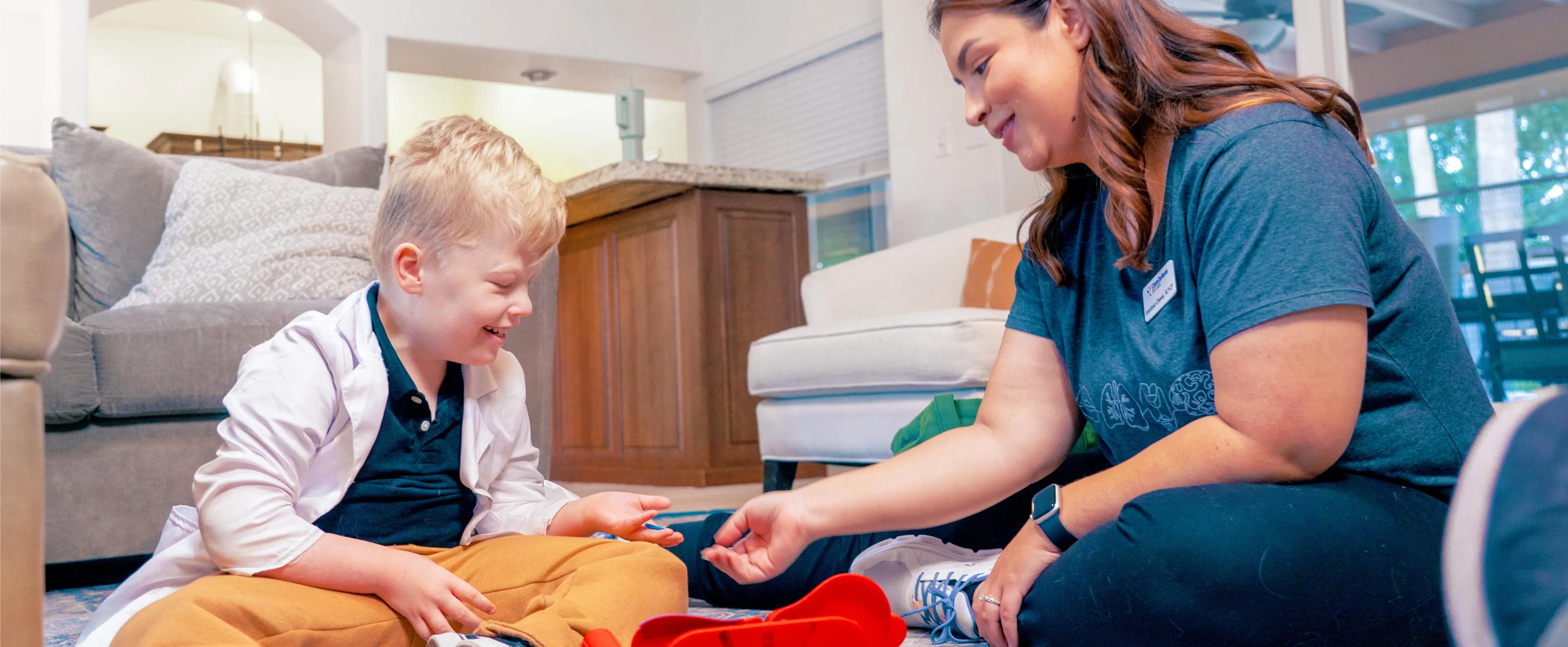 Woman in blue shirt sitting on the floor playing with a child