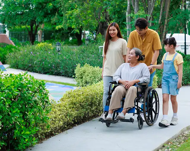A grandmother being pushed in a wheelchair outside by her family