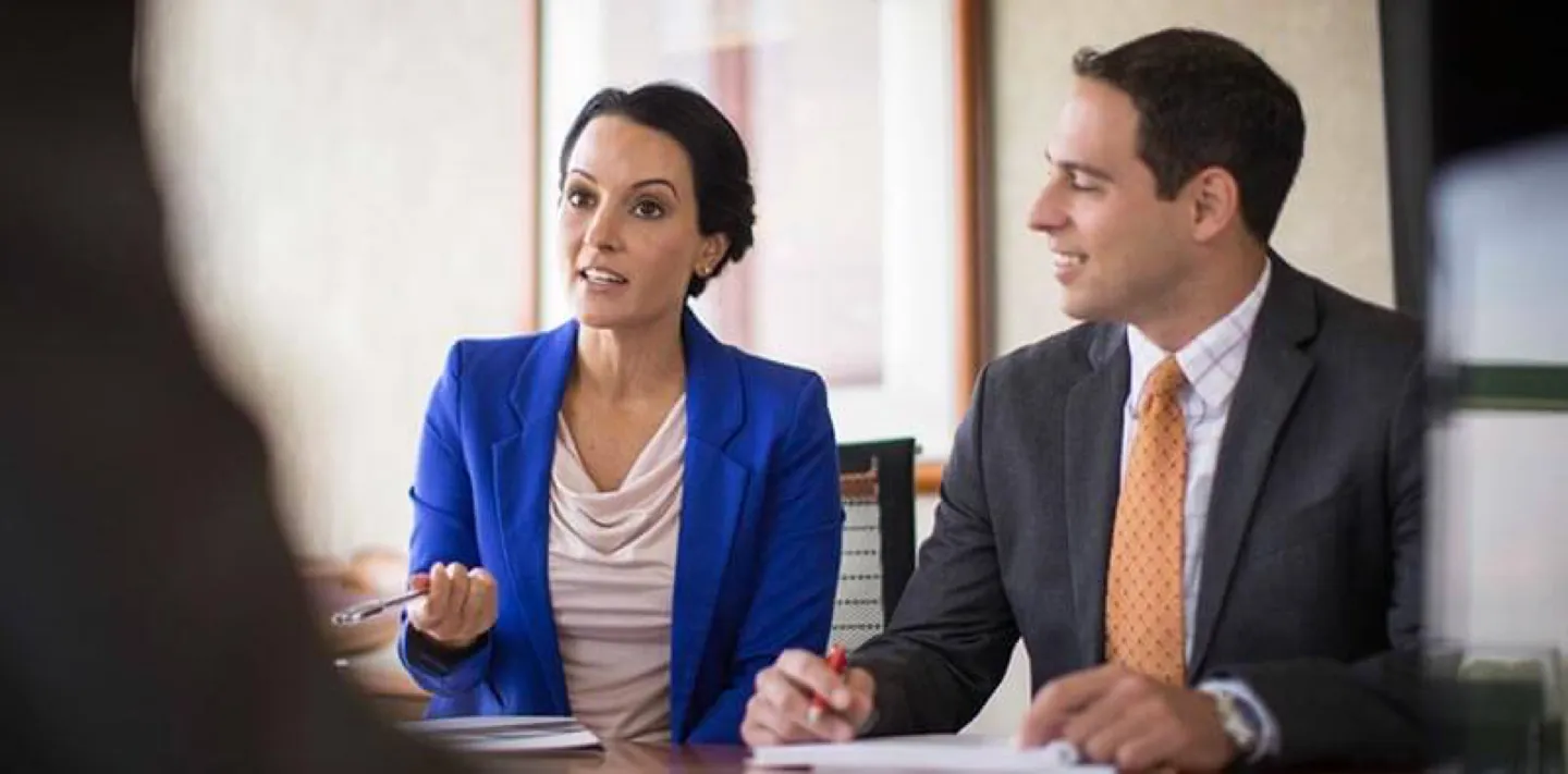 Two employees chatting with a client in office setting