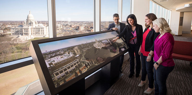 Employees looking at large computer screen showing the infrastructure of a building