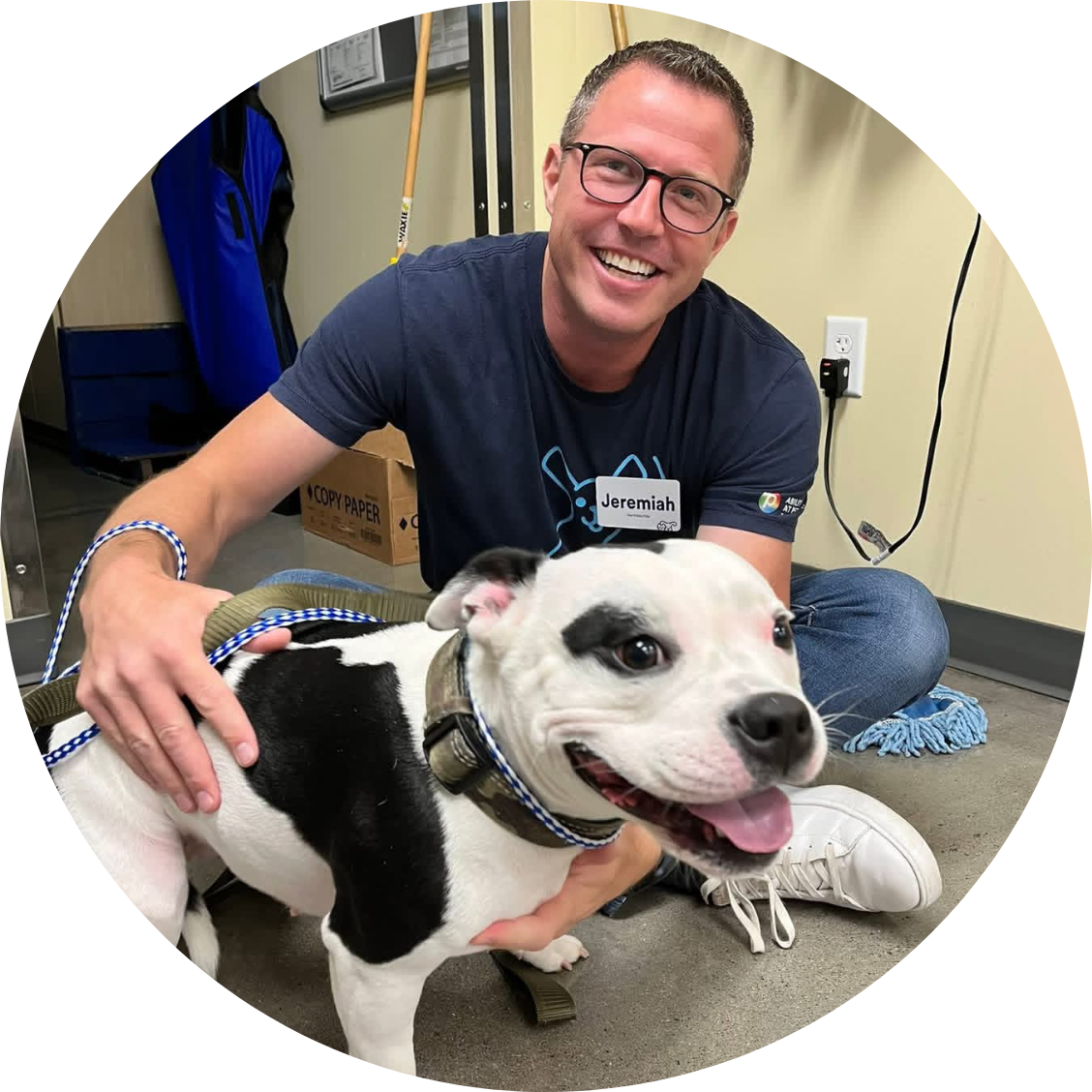 Petco partner smiling with a black-and-white dog inside a pet care store.