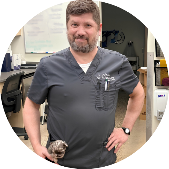 Vetco Total Care partner smiling in scrubs while holding a small kitten.